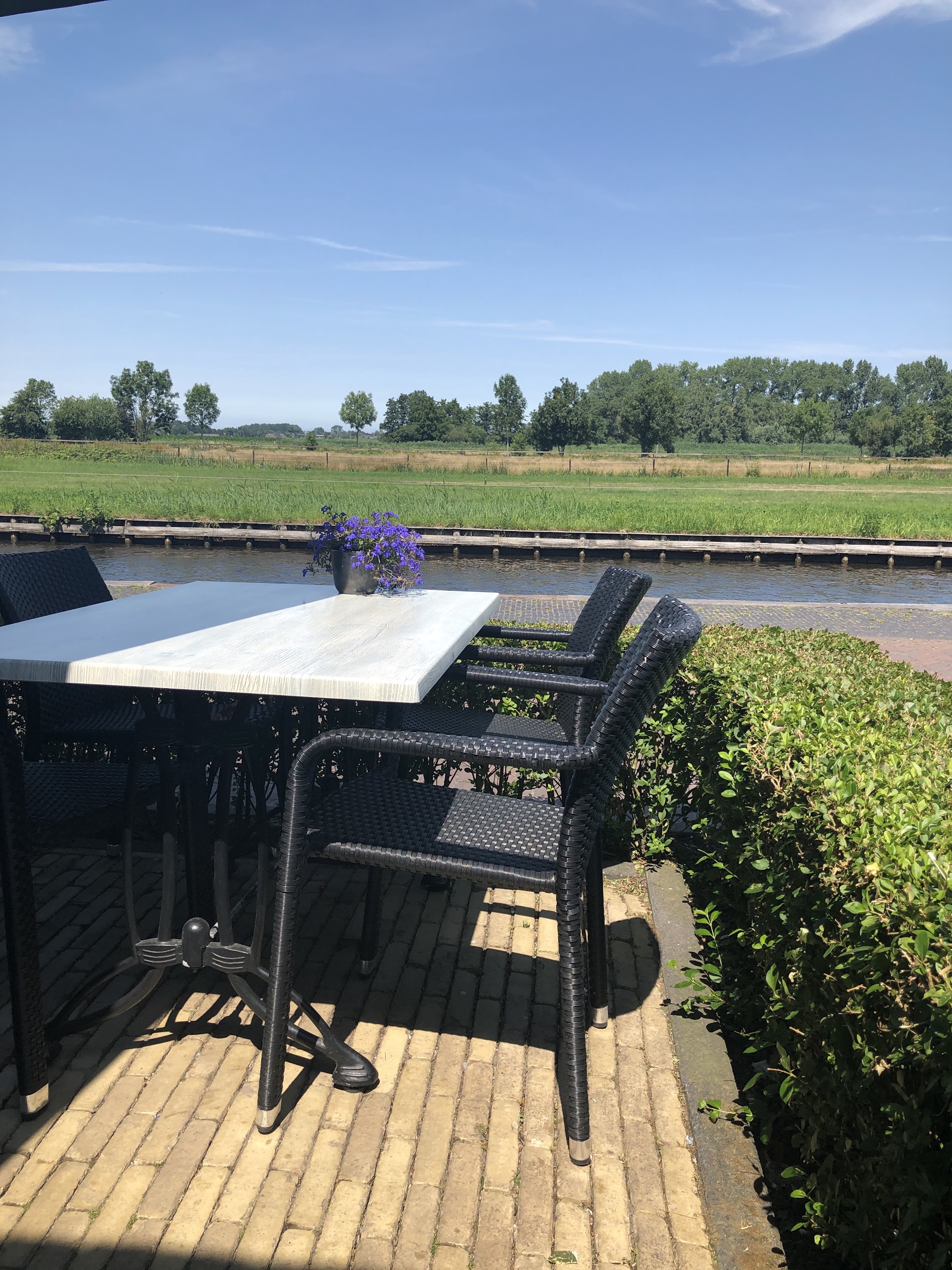 Een gedekte tafel op het terras van Canal Grande, met uitzicht over de gracht en de weilanden